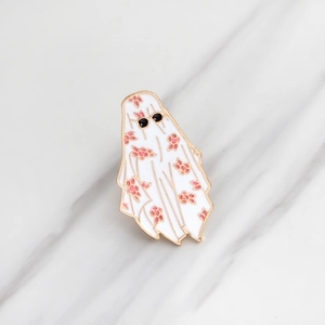 Cartoon white ghost enamel pin with sunglasses and floral pattern on marble background