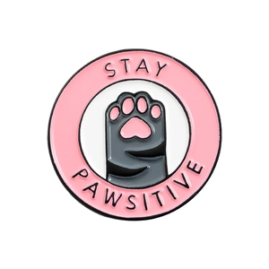 Round pink and grey Stay Pawsitive cat paw enamel pin with metal finish and cute lettering