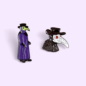 Detail view of two plague doctor enamel pins featuring purple robes and bird masks
