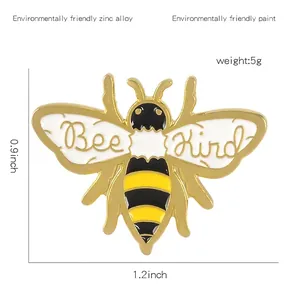 Broche en émail abeille avec inscription Bee Kind et ailes jaune noir sur fond blanc