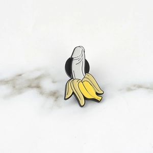 Funny enamel banana brooch pin with creative parody design on white marble surface