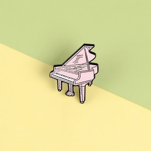 Détail d'une broche de piano en émail rose avec des lignes noires et touches en métal
