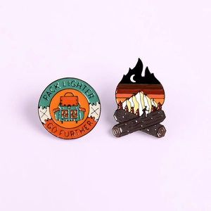 Set of two outdoor adventure enamel pins featuring hiking backpacks and campfire designs