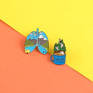 Detailed enamel pins featuring lung-shaped scenery and an Explore coffee cup design
