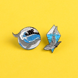Cartoon whale enamel pins set with wave patterns on a bright yellow background