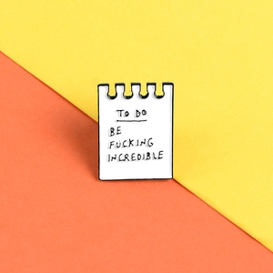Detail of notepad enamel pin with 'TO DO BE FUCKING INCREDIBLE' on yellow background