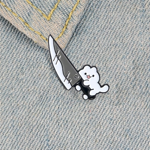 Cute white cartoon cat holding a large knife creative enamel pin on denim background