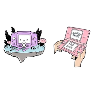 Cartoon gaming console enamel pins featuring purple retro handheld and pink dual screen