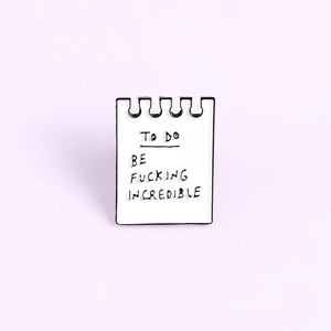 Cartoon enamel pin shaped like a notepad with BE FUCKING INCREDIBLE text design