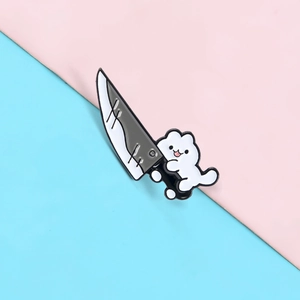 Macro shot of cartoon white cat holding a chef knife enamel pin on pastel background
