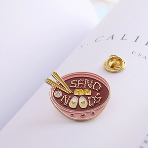 Creative enamel pin featuring ramen bowl with Send Noods text and golden butterfly clasp
