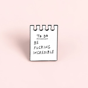 Cartoon notebook enamel pin with To Do Be Fucking Incredible slogan on pink background