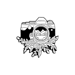 Retro camera enamel pin with floral and mountain landscape design in black and white