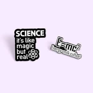 Minimalist science enamel pins featuring E=mc² and atomic designs on purple background