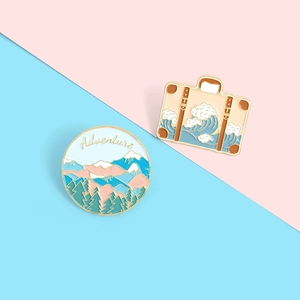 Detail of adventure mountain and wave enamel pins set on a dual-tone pastel background