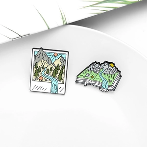 Kreative Emaille-Pins mit Berglandschaften im Polaroid- und Buchdesign für Naturliebhaber