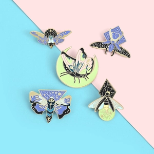 Detailed macro shot of five butterfly and insect enamel pins with celestial gold patterns