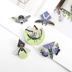 Detail view of moth and butterfly enamel pins with celestial and mystical motifs