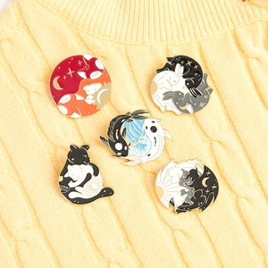 Five enamel pins with fox, rabbit, and koi designs in Yin Yang style on a knitted sweater