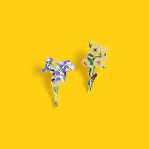Artistic Van Gogh inspired sunflower and iris flower enamel pins on a yellow background