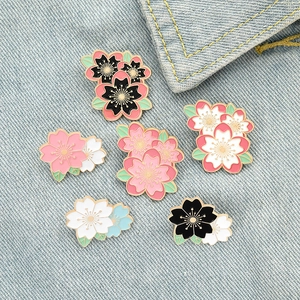 Set of creative cherry blossom enamel pins in various colors on denim background