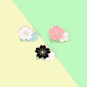 Détail de broches en émail en forme de fleurs de cerisier rose, blanc et noir