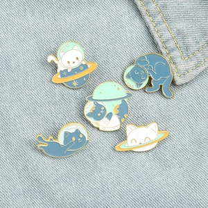 Set of five cute astronaut space cat enamel pins on blue denim fabric background
