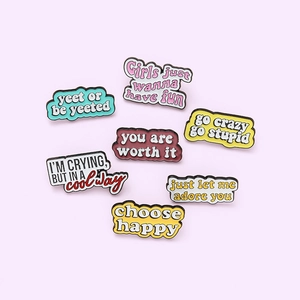 Lot de sept épinglettes émaillées colorées avec slogans anglais sur fond violet clair
