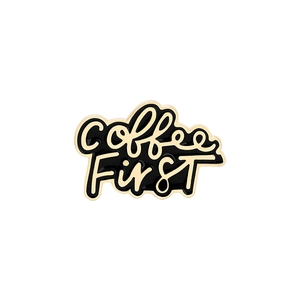 Dettaglio della spilla smaltata Coffee First con sfondo nero e bordo dorato