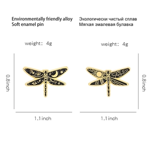 Detail view of dragonfly enamel pins with sun, moon and star patterns on alloy