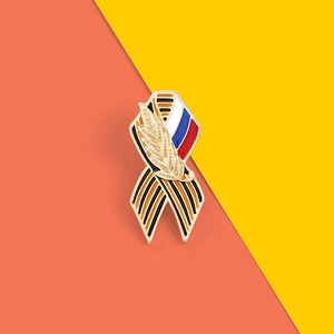 Vue détaillée d'une broche en ruban émaillé avec rayures noires et orange et drapeau