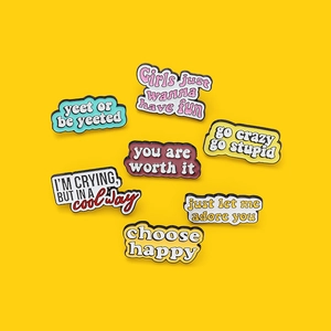 Ensemble de sept épinglettes en émail coloré avec slogans sur un fond jaune vif