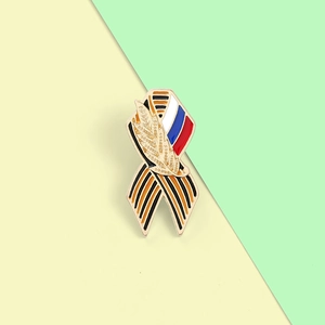 Détail de la broche en émail métallique avec rayures orange noires et motif d'épis de blé