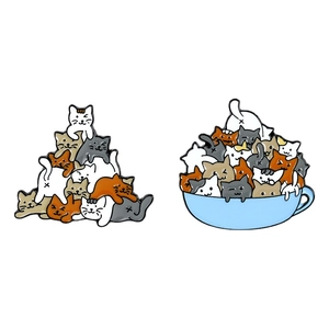 Cute enamel pins featuring colorful stacked cats and kittens playing in a light blue teacup