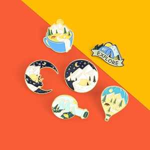 Close-up of 6 mountain landscape enamel pins featuring tent and campfire themes