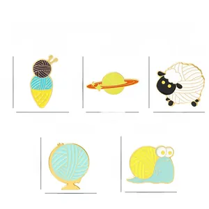 Detailed view of yarn ball enamel pins featuring sheep, globe, and snail designs