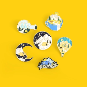 Detailed view of six outdoor camping enamel pins with mountains and explore theme on yellow