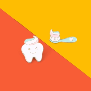 Detailed view of cute cartoon tooth and toothbrush enamel pins for dental care awareness