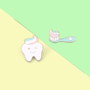 Detail of creative cartoon enamel pins featuring a smiling tooth and blue toothbrush