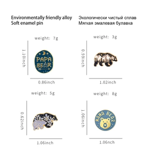Set of four cartoon polar bear enamel pins with forest silhouettes and letter carvings