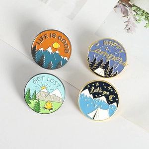 Set of four circular outdoor camping enamel pins with mountains and forest scenery