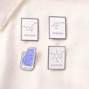 Macro detail of enamel science pins featuring molecular formulas and a cartoon mole