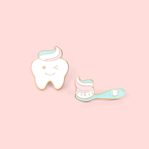 Creative cartoon tooth and toothbrush enamel pins set on a soft pink background