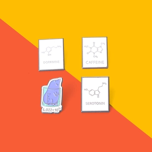 Detailed view of scientific enamel pins featuring dopamine, caffeine and serotonin symbols