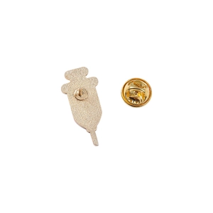 Golden syringe medical brooch back view with butterfly clasp on matte metal alloy surface