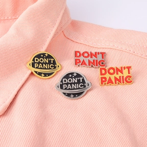 Don't Panic planet enamel pins and metal badges set pinned on pink denim fabric