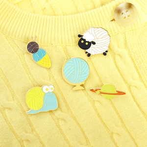 Creative enamel sheep and snail yarn pins on yellow knitted sweater accessory