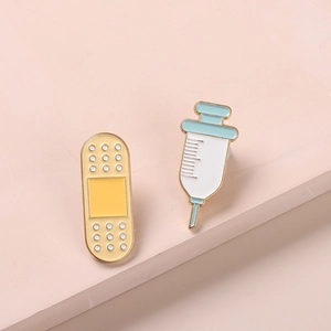 Creative medical enamel pins set with yellow band-aid and blue syringe on pink platform