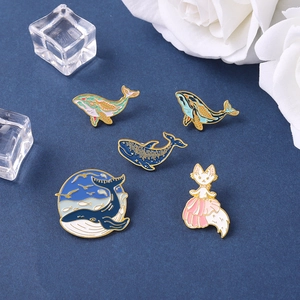 5-piece ocean enamel pin set with blue whales and pink fox on dark background