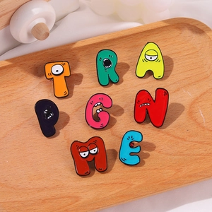 Detail of anthropomorphic colorful cartoon letter enamel brooches on a wooden tray
